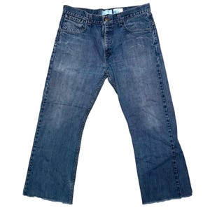 May include: Blue denim jeans with a classic five-pocket design. The jeans have a faded wash and a slight flare at the leg opening. The jeans have a button and zipper closure.
