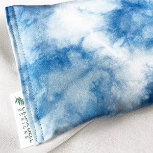 May include: A close-up of a blue and white tie-dye fabric. The fabric is soft and has a cloud-like pattern. A white tag with the text "CEDARWELL DESIGNS" is attached to the fabric.