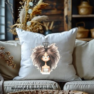 May include: A white pillow with a cartoon illustration of a girl with brown hair wearing a crown. The girl has large eyes and a surprised expression.