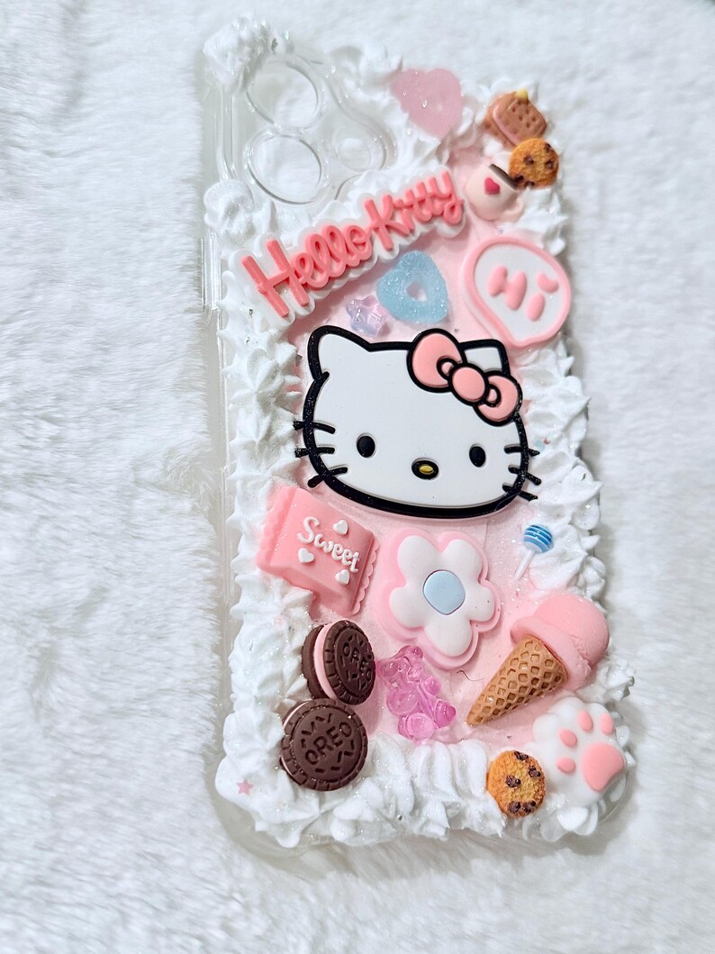 Pu&ograve; includere: Una custodia per telefono rosa e bianca Hello Kitty con un design Hello Kitty 3D, un design a spirale rosa e bianco e vari altri abbellimenti 3D tra cui biscotti, gelato e caramelle.