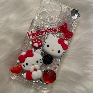 Puede incluir: Carcasa transparente para teléfono con personajes de Hello Kitty, lazos rojos, purpurina y pedrería.