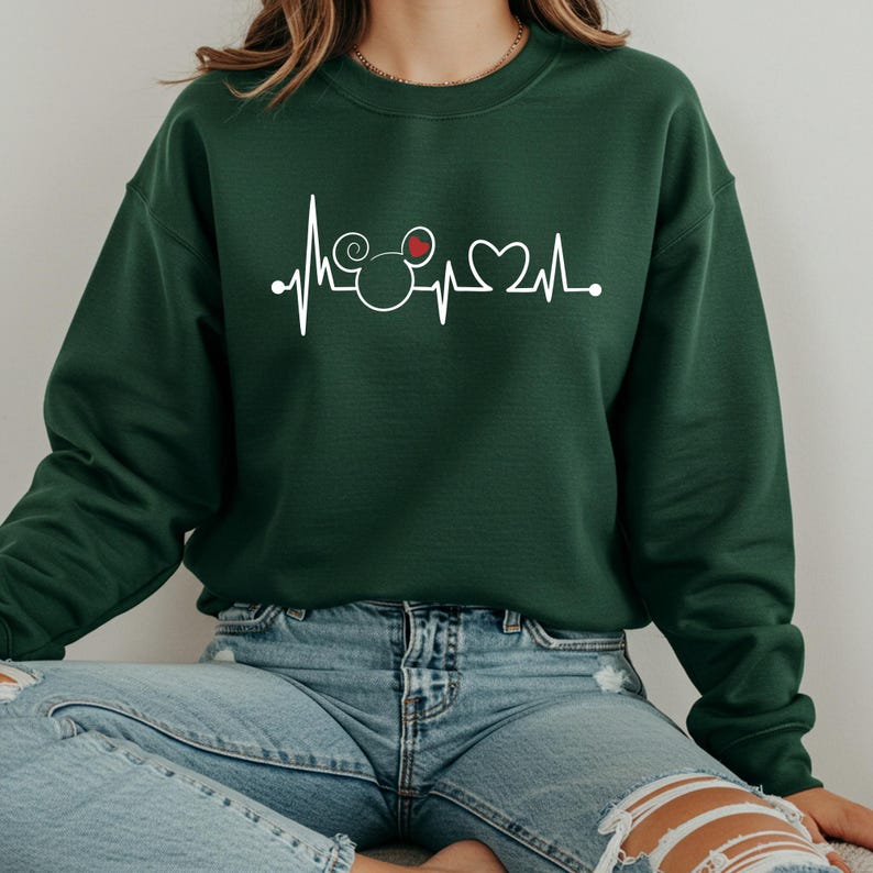 May include: A dark green sweatshirt with a white graphic of a heartbeat with a Mickey Mouse head and a heart in the middle.