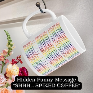 Puede incluir: Taza de café de cerámica blanca con un diseño de arcoíris que dice "SHHH... SPIKED COFFEE" repetido en un patrón.