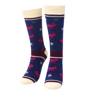 May include: Knee-high socks with a navy blue backdrop, patterned with pink moose, pink flowers, and green foliage. The top and toe are cream-coloured, with a burgundy band at the ankle. A fun and colourful design for everyday wear.