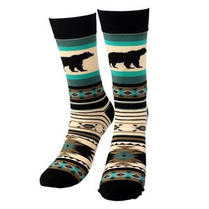 May include: A pair of socks with a black bear silhouette on a cream background, teal and black stripes, and a geometric pattern. The socks have black toes and cuffs.