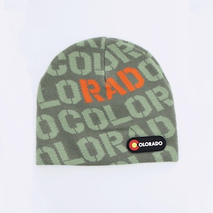 Pode incluir: Um gorro de malha verde com a palavra "COLORADO" em letras laranja e verdes. O gorro tem um pequeno patch com as cores da bandeira do Colorado. Um acessório de inverno.