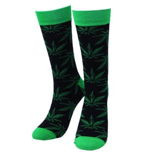 May include: A pair of black socks with a green cannabis leaf pattern. The socks have green cuffs and toes. The socks are made of a soft, comfortable material.