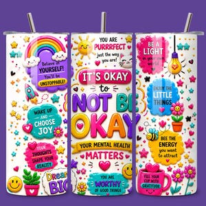 May include: A white tumbler with a stainless steel straw, decorated with colorful graphics and motivational phrases. The design includes a rainbow, stars, flowers, and the text "It's Okay to Not Be Okay." The tumbler promotes positivity and mental wellness.