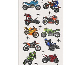 May include: A white rectangular towel featuring colorful illustrations of various motorcycles. The motorcycles are in different colors, including blue, orange, green, and red, and are set against a background of black starbursts.