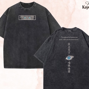 Op de afbeelding: Donkergrijs t-shirt met een geborduurd oogontwerp. De voorkant heeft een oogontwerp in een rechthoek. De achterkant heeft tekst en een oogafbeelding. De tekst luidt "Throughout the heavens and earth, I alone am the honored one."