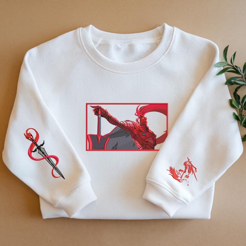 Puede incluir: Sudadera blanca con ilustraciones bordadas. El dise&ntilde;o presenta una ilustraci&oacute;n roja y gris de una figura sosteniendo una espada, enmarcada en rojo. Detalles bordados adicionales incluyen una espada con una cinta roja y una figura m&aacute;s peque&ntilde;a en la manga.