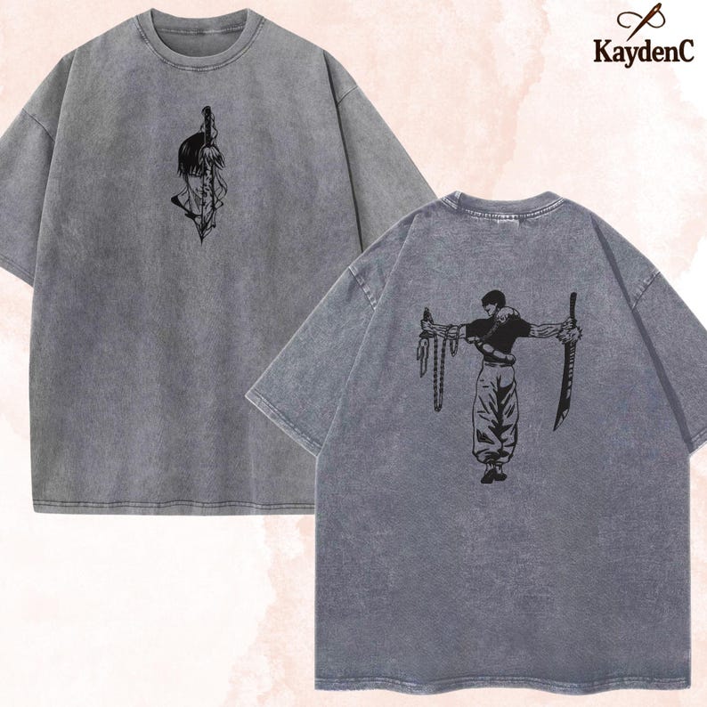 Puede incluir: Dos camisetas grises con dise&ntilde;os gr&aacute;ficos negros. Una camiseta presenta una espada y una cara, la otra tiene una figura sosteniendo espadas. Las camisetas tienen un aspecto vintage y lavado. El logo de KaydenC est&aacute; en la esquina superior derecha.