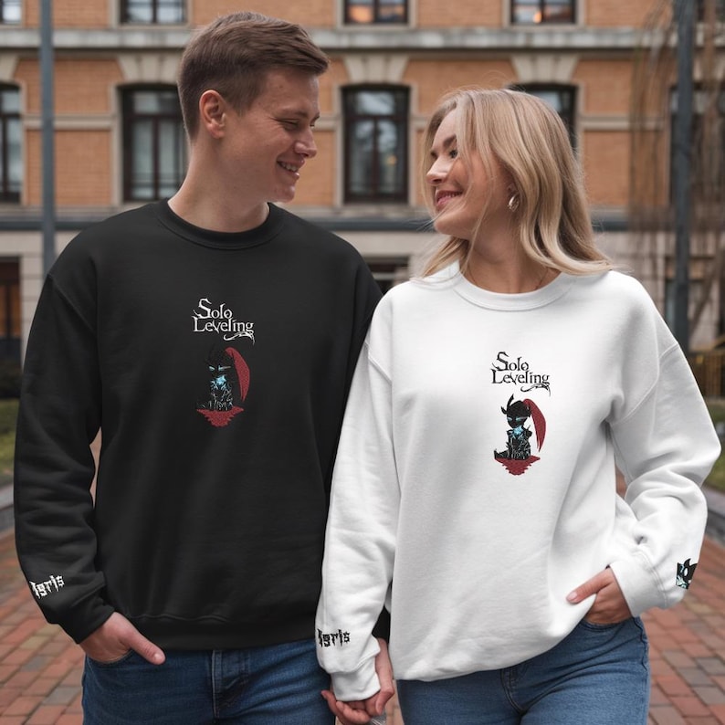 May include: Two people wearing black and white sweatshirts with the text "Solo Leveling" and a graphic of a character from the anime. The sweatshirts have the word "igris" on the cuffs.