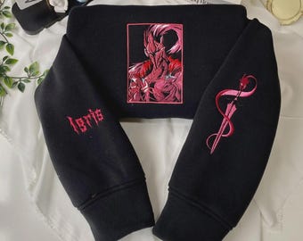 May include: A black long-sleeve sweatshirt featuring a rectangular pink and red embroidered graphic of a knight on the chest. The left sleeve displays the embroidered text "Igris" in red, while the right sleeve features a red sword emblem.