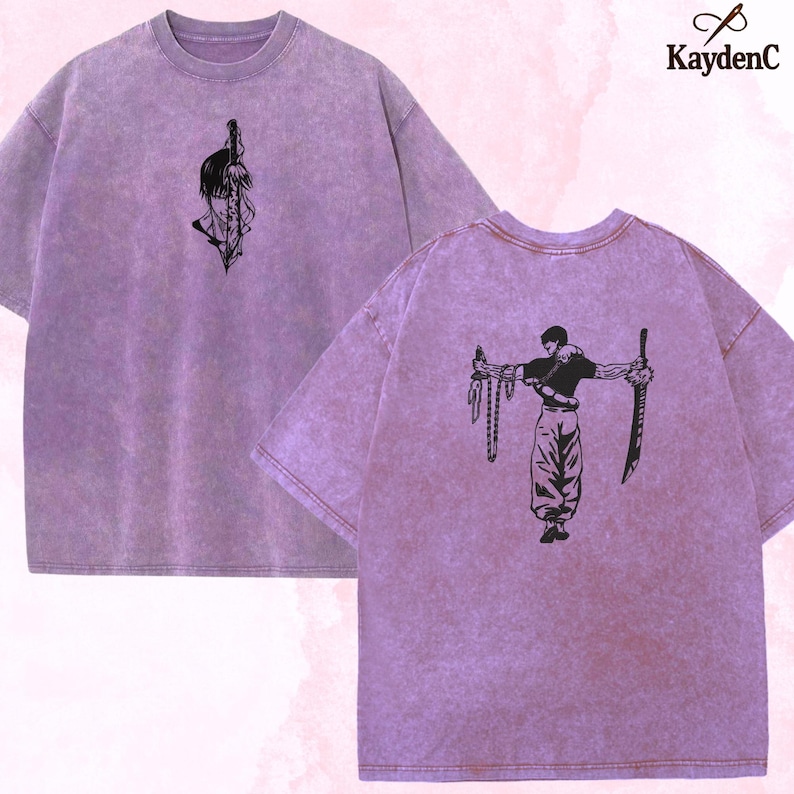 Puede incluir: Dos camisetas lavanda con dise&ntilde;os gr&aacute;ficos negros. Una camiseta presenta una cara estilizada y una espada, la otra una figura con armas. Las camisetas tienen un aspecto vintage texturizado. El logotipo de KaydenC est&aacute; en la esquina superior derecha.