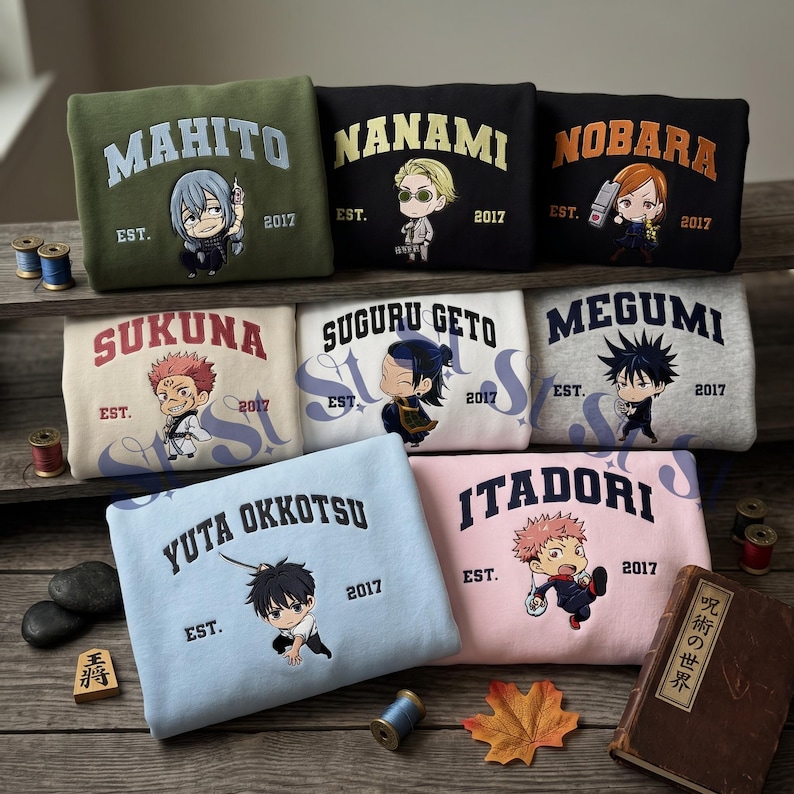 Może przedstawiać: Kolekcja ośmiu złożonych bluz w r&oacute;żnych kolorach, każda z ilustracją postaci z anime, nazwą czcionką łukową oraz napisem EST. 2017. Bluzy są wyeksponowane na drewnianych p&oacute;łkach wraz z małymi szpulkami nici.