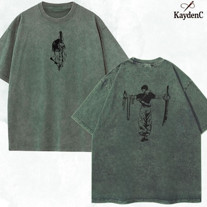 Puede incluir: Camiseta verde de gran tama&ntilde;o con gr&aacute;ficos negros en la parte delantera y trasera. El gr&aacute;fico frontal es una imagen estilizada de una persona con una espada. El gr&aacute;fico trasero es una persona con espadas. La marca "KaydenC" est&aacute; en la esquina superior derecha.