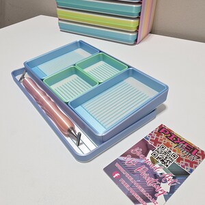 May include: A light blue diamond painting tray set with four green and blue compartments. A pink stylus and a business card with the text "Pixel Pages 3D Printing" are also visible.