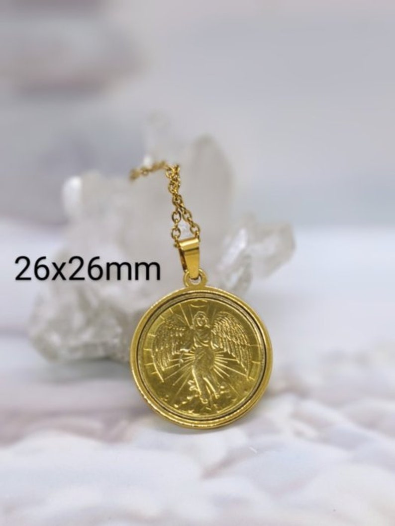 Puede incluir: Collar dorado con un colgante redondo que representa un &aacute;ngel con alas. El colgante mide 26 mm de di&aacute;metro.