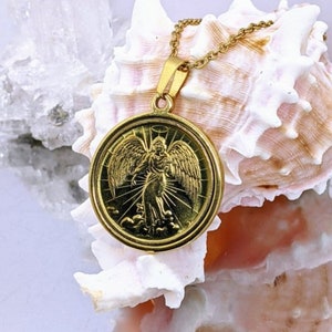 Puede incluir: Collar con colgante de oro que presenta un &aacute;ngel detallado con alas, sobre un fondo de nubes y rayos de luz. El colgante est&aacute; unido a una delicada cadena de oro.