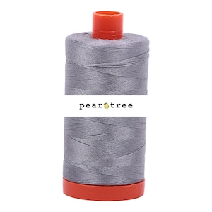 May include: A spool of gray thread with an orange top and base. The thread is tightly wound, and the label reads "pear tree". This thread is likely used for sewing, quilting, or other textile crafts.