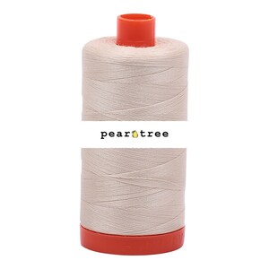 May include: A spool of beige thread with an orange top and base. The thread is tightly wound, and the label reads "pear tree" in black text. The thread is likely used for sewing, embroidery, or other crafts.