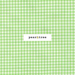 May include: A close-up of a green and white gingham pattern fabric. The fabric has a repeating square pattern. A white rectangle with the text "pear tree" and a pear graphic is centered on the fabric.
