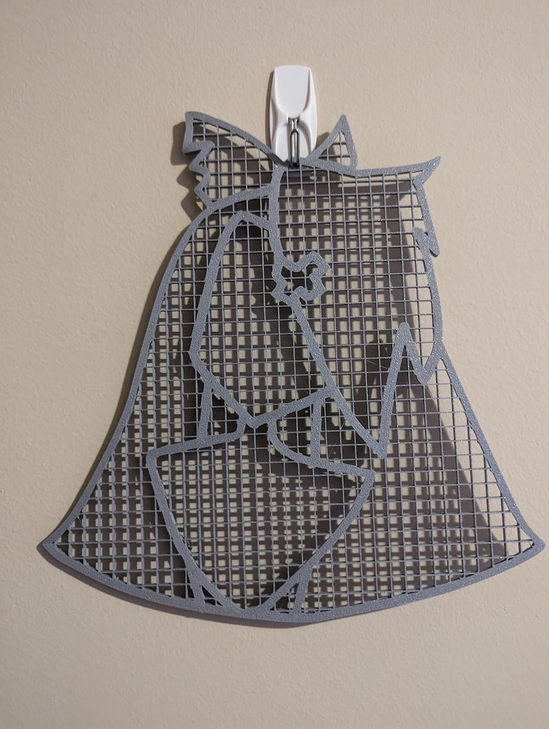 May include: A gray metal wall decor in the shape of a dog's head. The metal is cut out in a grid pattern, creating a shadow effect.