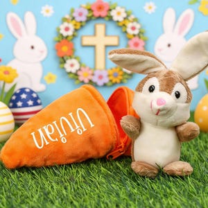 May include: An Easter-themed image featuring a plush bunny and an orange carrot-shaped bag with the name "Vivian" in white. Colorful Easter eggs and floral decorations are in the background, creating a festive scene.