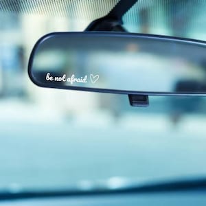 May include: A rearview mirror with a white vinyl sticker that reads "be not afraid" with a small heart symbol.