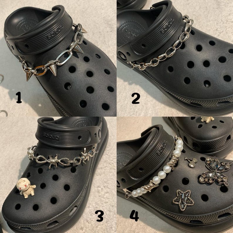 May include: Four black clogs, each adorned with different decorative chains and charms. One features a chain with spikes, another a simple chain, a third has barbed wire, and the last has pearls and charms including a butterfly and star.