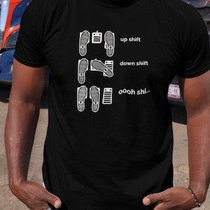 Puede incluir: Camiseta negra con un gráfico blanco de un pedal de acelerador de coche y el texto "up shift", "down shift" y "ooh shi..."