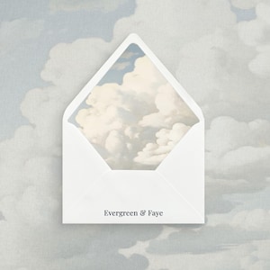 May include: A white envelope featuring the text "Evergreen & Faye". The open envelope displays a painting of a cloudy sky. The background is a light blue and grey cloudy sky.