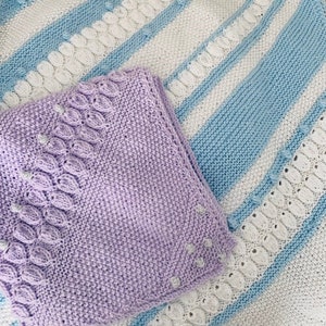 Puede incluir: Dos mantas de bebé de punto, una con un patrón de rayas azul claro y blanco y la otra de color morado claro.