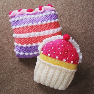 May include: Two knitted pillows shaped like cupcakes. One is a pink and white layered cupcake with white frosting and the other is a yellow and pink cupcake with white frosting.