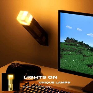 May include: A Minecraft-themed night light shaped like a torch, with a glowing orange cube at the top. The light is mounted on a wall next to a computer monitor displaying a Minecraft scene. The text "LIGHTS ON UNIQUE LAMPS" is visible below the light.