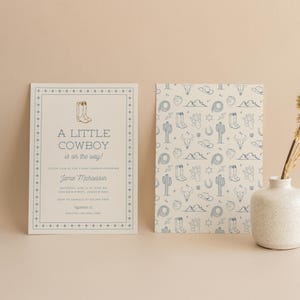 May include: A baby shower invitation with a blue and white pattern of cowboy boots, cacti, and other western motifs. The text reads "A Little Cowboy is on the way!" and includes the name Jamie Michaelson.