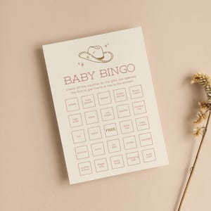 K&ouml;nnte beinhalten: Eine cremefarbene Baby-Bingo-Spielkarte mit einer Cowboyhut-Grafik. Der Text lautet "Baby Bingo" und enth&auml;lt eine Liste von Babyartikeln zum Abhaken. Die Karte ist f&uuml;r ein Babyparty-Spiel gedacht.