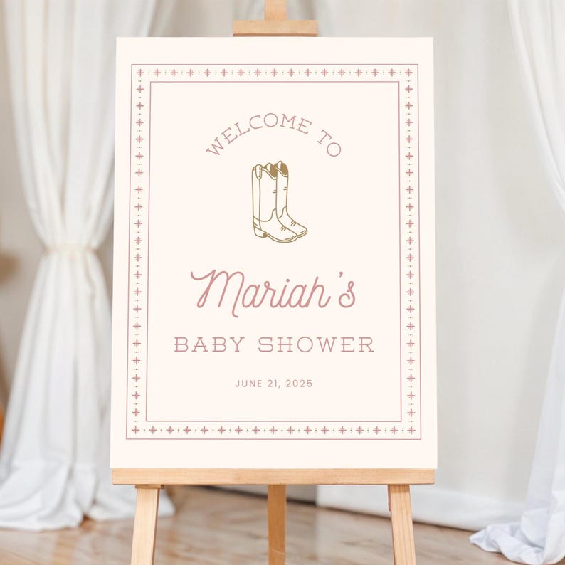 K&ouml;nnte beinhalten: Ein cremefarbenes Schild auf einer Holzstaffelei mit dem Text "Welcome to Mariah's Baby Shower" in einer Mischung aus Schriftarten. Das Schild enth&auml;lt eine Illustration von Cowboy-Stiefeln und das Datum 21. Juni 2025.