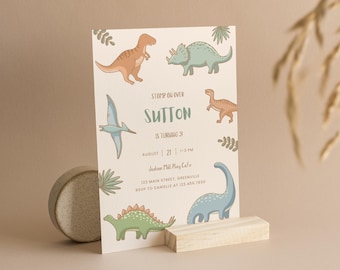 Peut inclure: Une invitation à une fête d'anniversaire sur le thème des dinosaures avec un fond brun clair. L'invitation présente une variété de dinosaures colorés, dont un stégosaure vert, un brachiosaure bleu, un tyrannosaure rex brun, un tricératops bleu et un ptérodactyle. Le texte sur l'invitation se lit comme suit : "STOMP ON OVER SUTTON IS TURNING 31 AUGUST 21 1-3 PM Jadson Mill Play Cafe 123 MAIN STREET, GREENVILLE RSVP TO DANIELLE AT 123.456.7890"