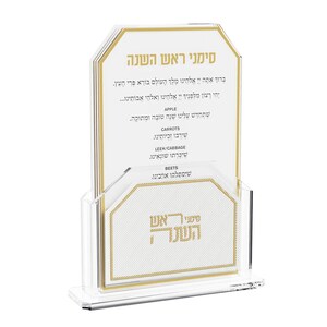 May include: Clear acrylic table sign with gold trim and Hebrew text. The sign lists traditional foods for Rosh Hashanah, including apple, carrots, leek/cabbage, and beets. The sign is in a clear acrylic holder.