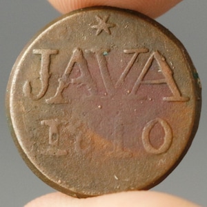 Puede incluir: Primer plano de una moneda de bronce con la palabra "JAVA" y el número "10" inscritos. Una estrella está encima de la palabra "JAVA". La moneda tiene un aspecto desgastado, con signos visibles de edad y desgaste.