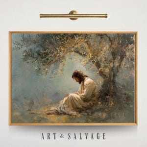 May include: A framed painting with a religious theme. The artwork depicts a figure in white robes seated under a tree. The painting has a gold frame and is mounted on a white wall. The text "ART & SALVAGE" is visible at the bottom.