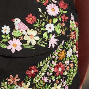 Pode incluir: Tecido preto com flores bordadas coloridas e um pequeno p&aacute;ssaro. O bordado &eacute; feito com fita e fio.