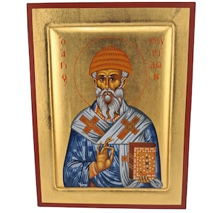 Pode incluir: Um ícone religioso retangular apresentando uma figura barbuda usando um gorro laranja e vestes azuis com uma estola branca adornada com cruzes. A figura segura um livro e faz um gesto. O fundo é dourado com texto em vermelho.