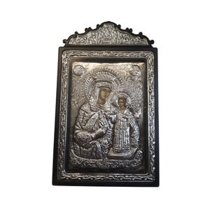 Könnte beinhalten: Silberfarbene religiöse Ikone, die eine Mutter und ein Kind zeigt, in einem schwarzen Rahmen. Die Ikone weist detaillierte Reliefarbeiten und Inschriften auf. Der obere Teil des Rahmens hat ein verziertes Design.