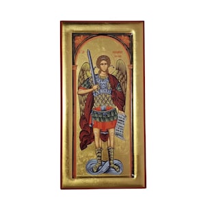 Op de afbeelding: Een rechthoekig religieus icoon met een gevleugelde figuur in harnas die een zwaard en een perkamentrol vasthoudt. De figuur draagt een rode mantel over een tuniek met patronen en beenwindsels. De achtergrond is goud met een boogvormig kader.