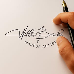 May include: A black and gold fountain pen held over a white paper with the words "Willow Brooke Makeup Artist" in elegant script. The logo is in black, with the words in a circular arrangement.
