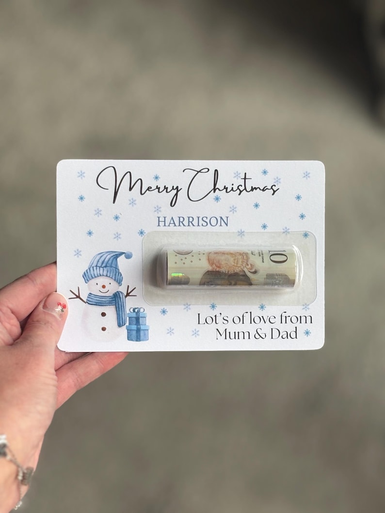 May include: A Christmas-themed gift card with a snowman illustration, snowflakes, and the text "Merry Christmas" and "Lots of love from Mum & Dad". The card holds a rolled-up bill.