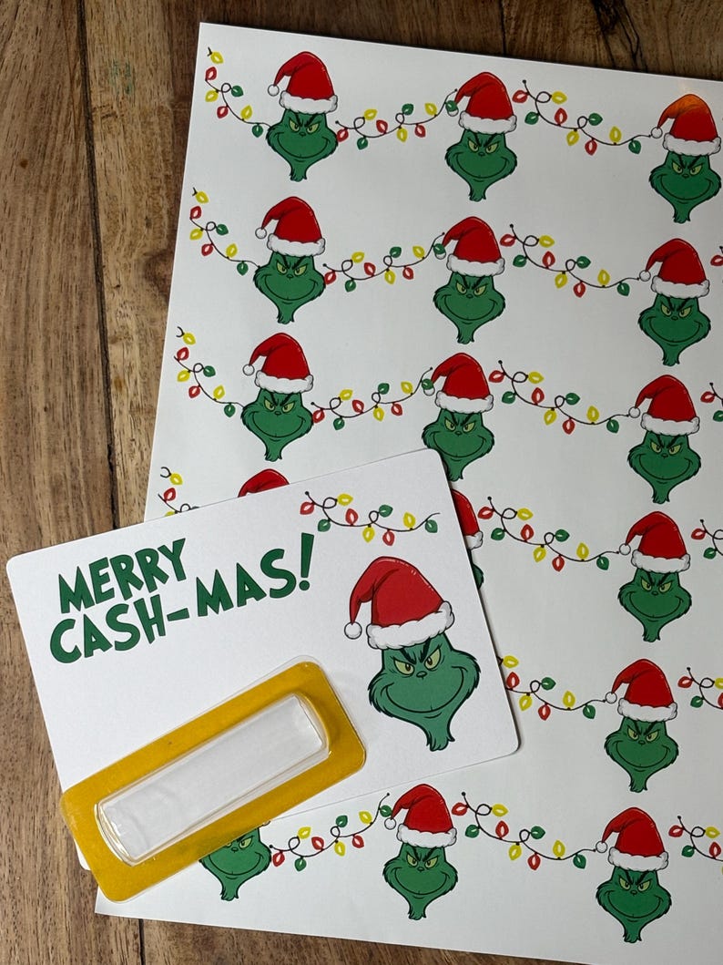 Puede incluir: Hojas de papel blanco con un patr&oacute;n repetido de un personaje de dibujos animados verde con un gorro de Pap&aacute; Noel y luces de cadena. Una hoja tiene el texto "MERRY CASH-MAS!" en verde, con un rect&aacute;ngulo amarillo.